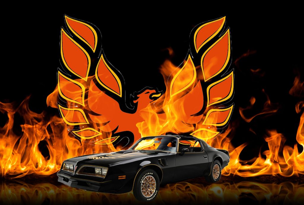 Black and gold 1977 Pontiac Firebird Trans Am in front of flames.